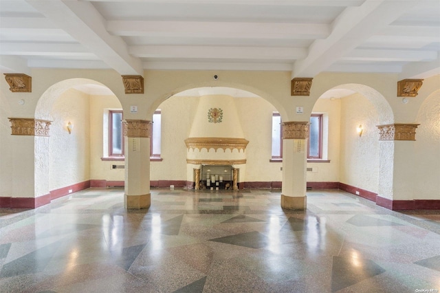 empty room with a large fireplace and beamed ceiling