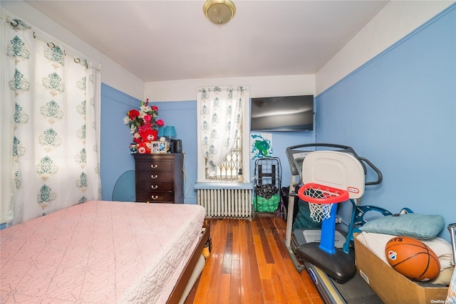 bedroom featuring radiator and hardwood / wood-style flooring