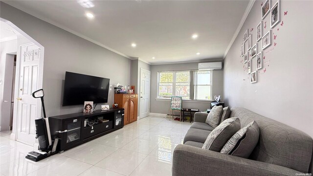 living room featuring baseboards, arched walkways, ornamental molding, a wall mounted air conditioner, and light tile patterned flooring