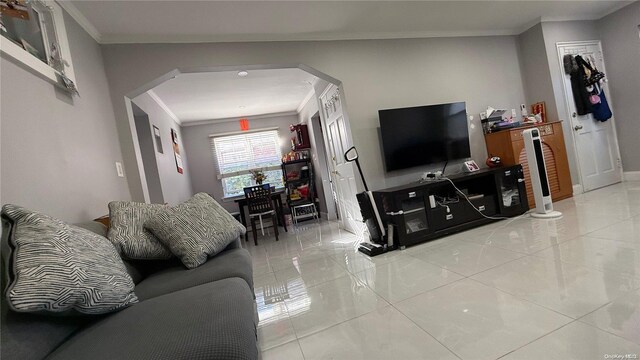 living room featuring light tile patterned floors, baseboards, and ornamental molding