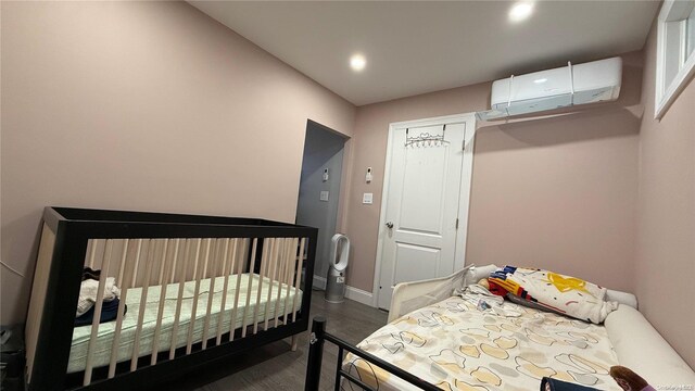 bedroom featuring recessed lighting, dark wood-style flooring, a wall mounted air conditioner, and baseboards