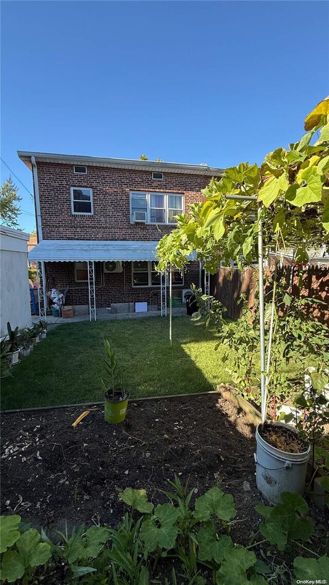 back of property featuring a patio, brick siding, a lawn, and fence