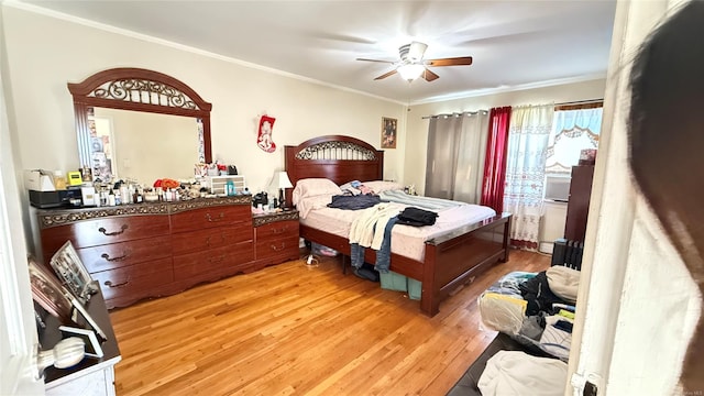 bedroom featuring ornamental molding, light wood finished floors, and a ceiling fan