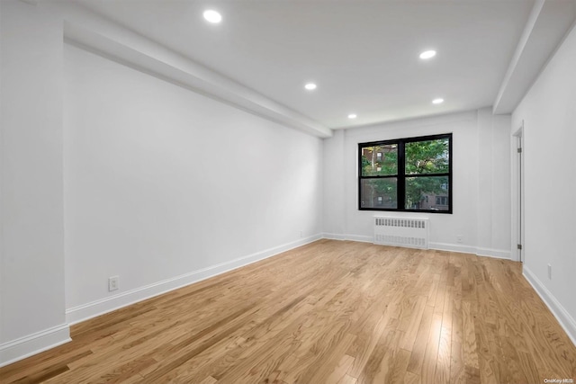 unfurnished room featuring light hardwood / wood-style floors and radiator heating unit