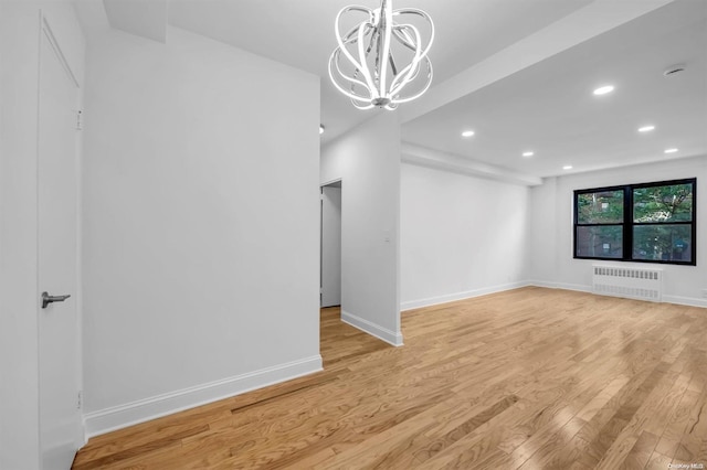 interior space featuring light wood-type flooring, an inviting chandelier, and radiator