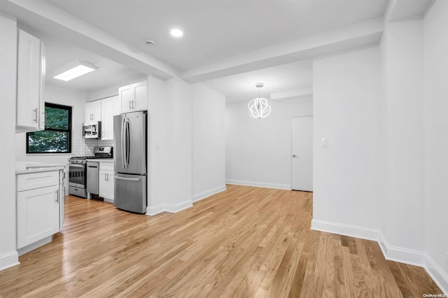 kitchen featuring white cabinets, light hardwood / wood-style floors, appliances with stainless steel finishes, and pendant lighting