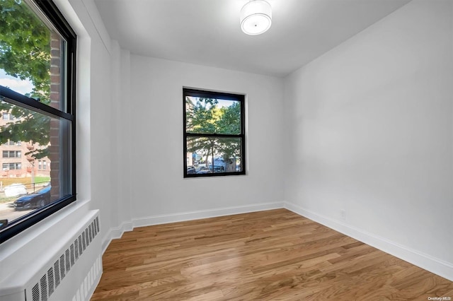 empty room with radiator heating unit and light hardwood / wood-style floors