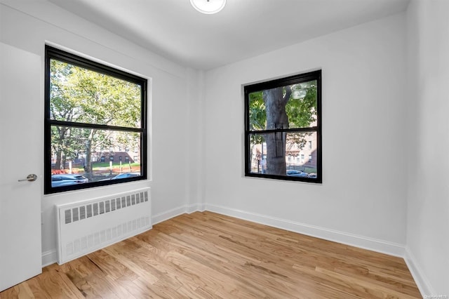 unfurnished room featuring radiator and light hardwood / wood-style flooring