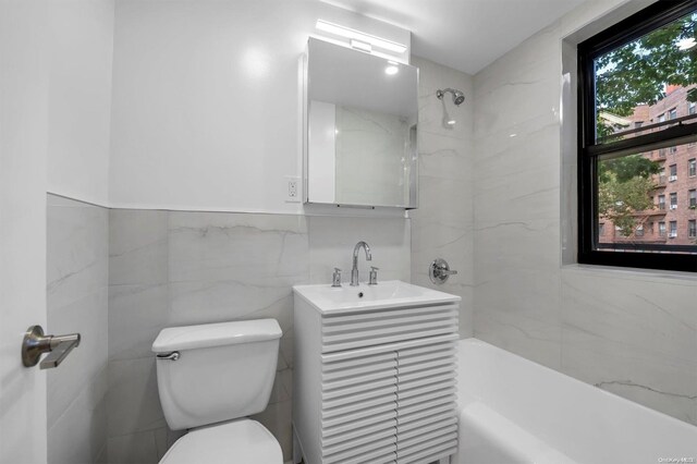 full bathroom with tiled shower / bath, vanity, tile walls, and toilet