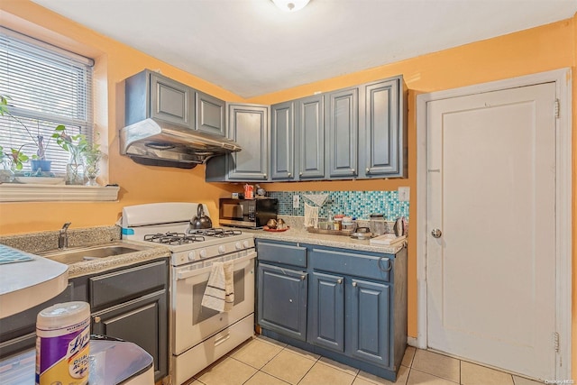 kitchen featuring gray cabinets, sink, light tile patterned floors, and white range with gas stovetop