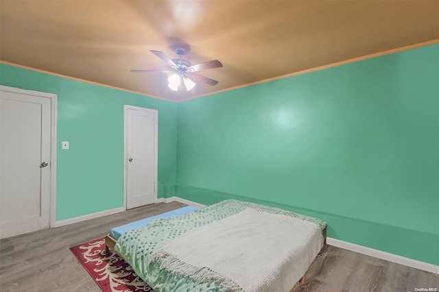 bedroom featuring ceiling fan, crown molding, and hardwood / wood-style flooring