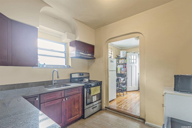 kitchen with sink, white fridge, light hardwood / wood-style floors, and stainless steel range with gas stovetop