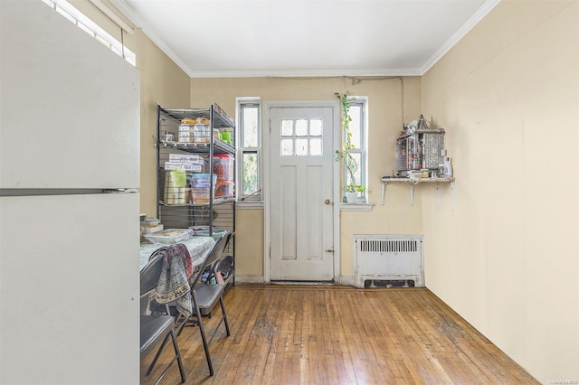 entryway featuring wood-type flooring, crown molding, and radiator