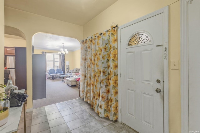 carpeted entryway featuring an inviting chandelier