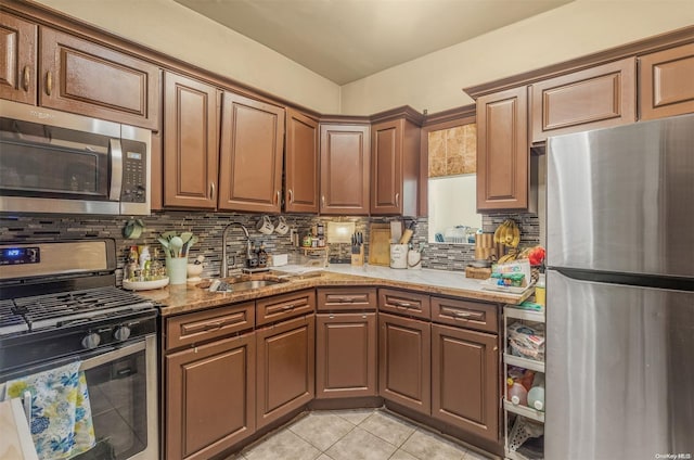 kitchen with backsplash, sink, light stone countertops, light tile patterned floors, and stainless steel appliances