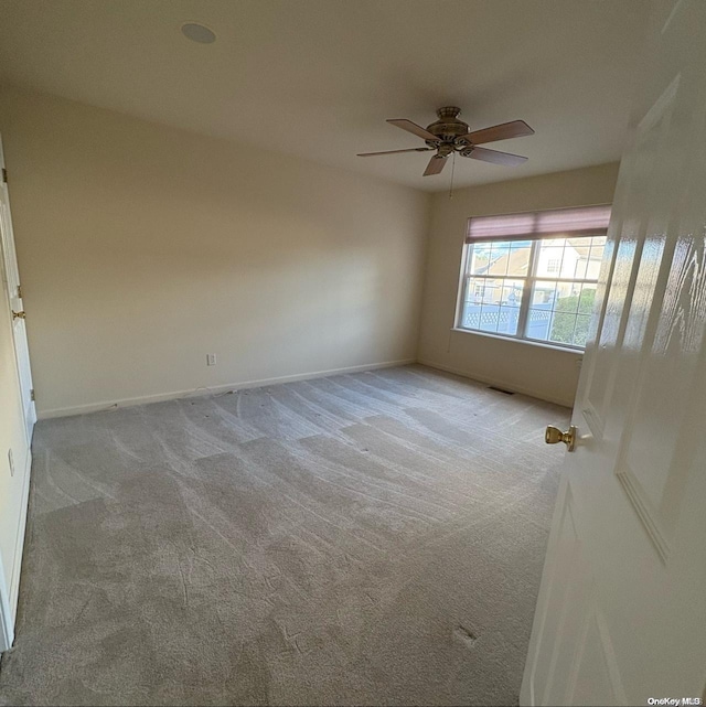 spare room with ceiling fan and light carpet