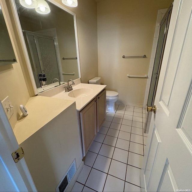 bathroom with vanity, toilet, a shower with door, and tile patterned flooring