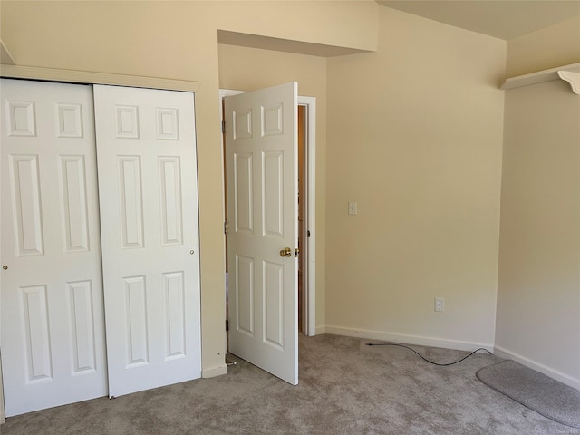 unfurnished bedroom with light colored carpet and a closet