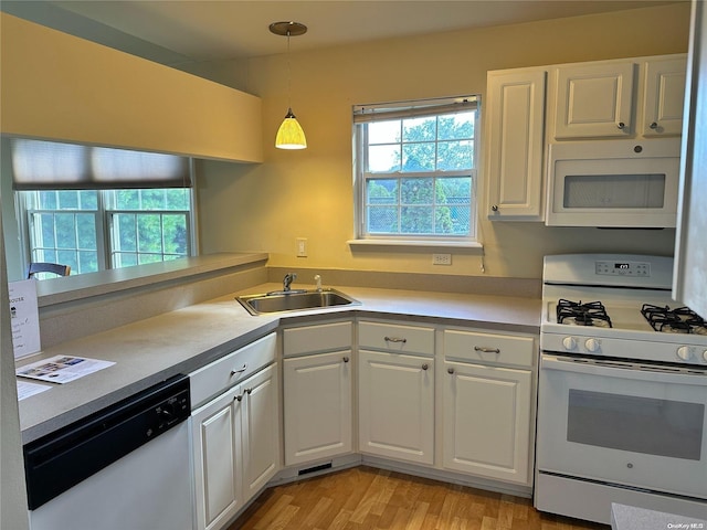 kitchen with pendant lighting, sink, white appliances, white cabinetry, and a healthy amount of sunlight