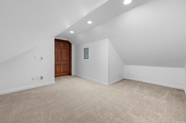 additional living space featuring light carpet, electric panel, and vaulted ceiling