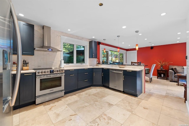 kitchen featuring hanging light fixtures, stainless steel appliances, wall chimney range hood, kitchen peninsula, and decorative backsplash