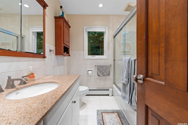 full bathroom featuring a baseboard radiator, tile patterned floors, combined bath / shower with glass door, toilet, and tile walls