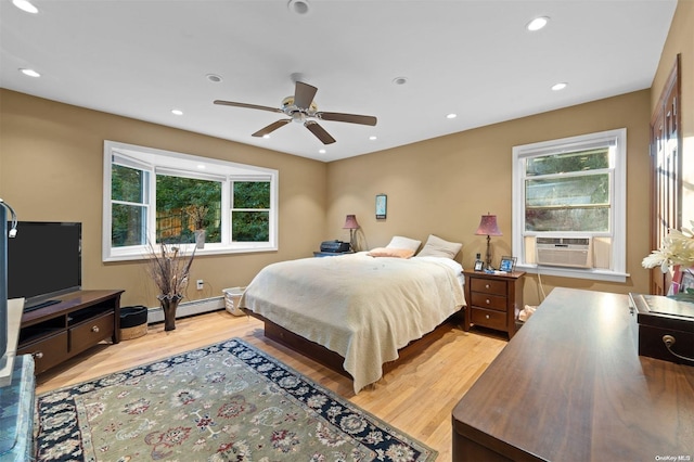 bedroom featuring ceiling fan, cooling unit, light wood-type flooring, and a baseboard heating unit