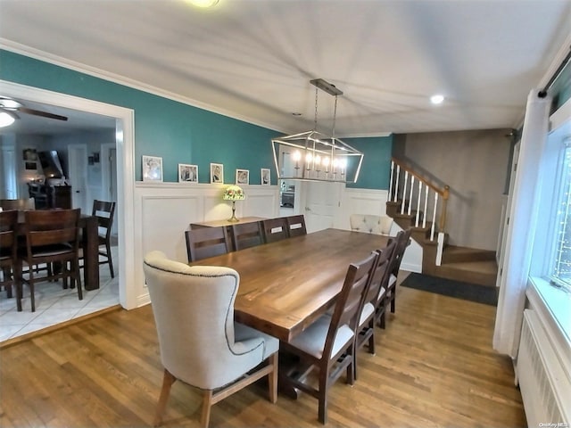 dining area featuring ceiling fan with notable chandelier, hardwood / wood-style flooring, radiator, and crown molding