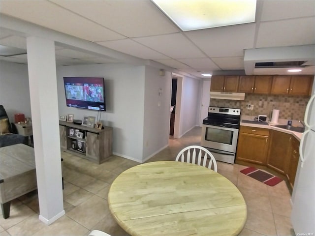 kitchen featuring a drop ceiling, light tile patterned floors, white refrigerator, decorative backsplash, and stainless steel range with electric cooktop