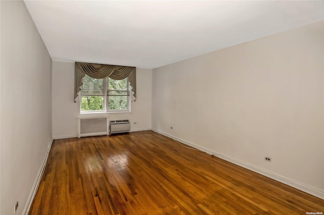 spare room with radiator heating unit and dark wood-type flooring