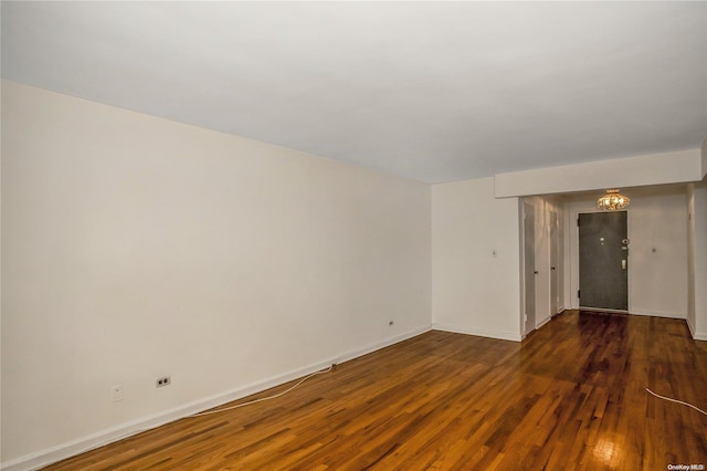 spare room featuring dark hardwood / wood-style floors and an inviting chandelier