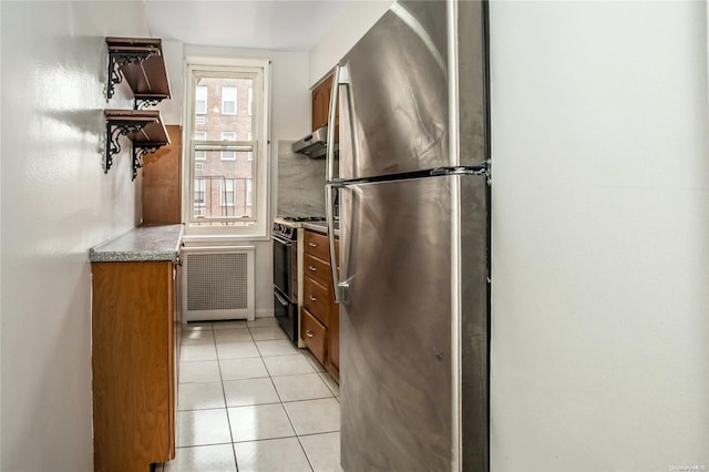 kitchen featuring stainless steel fridge, black gas stove, light tile patterned floors, and a wealth of natural light