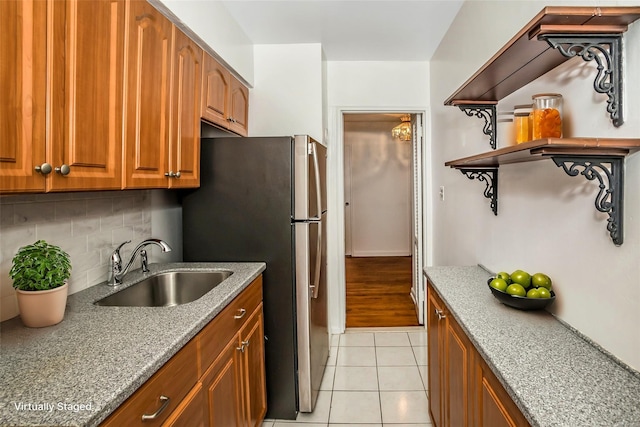 kitchen with decorative backsplash, light stone counters, sink, stainless steel refrigerator, and light tile patterned flooring