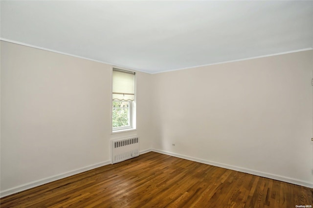 empty room featuring wood-type flooring, crown molding, and radiator