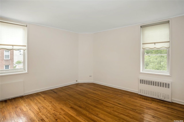 unfurnished room featuring radiator heating unit, wood-type flooring, and ornamental molding