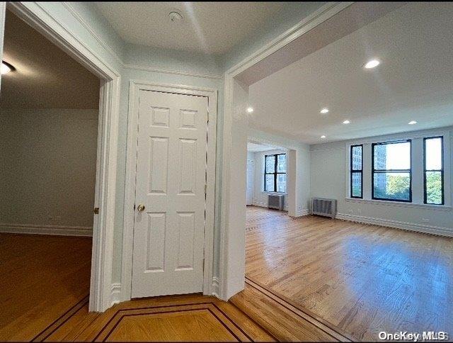 corridor with hardwood / wood-style flooring, radiator, and a wealth of natural light