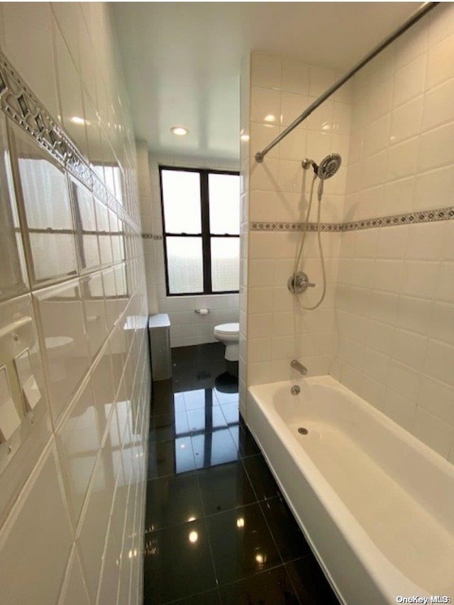 bathroom with tile patterned flooring, tiled shower / bath, and toilet