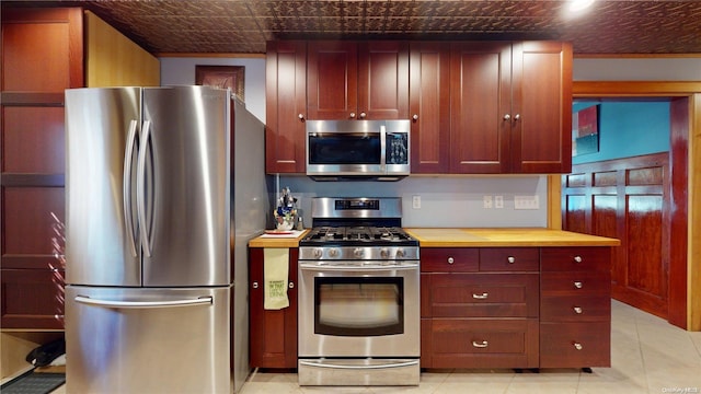 kitchen featuring wood counters, appliances with stainless steel finishes, and light tile patterned floors