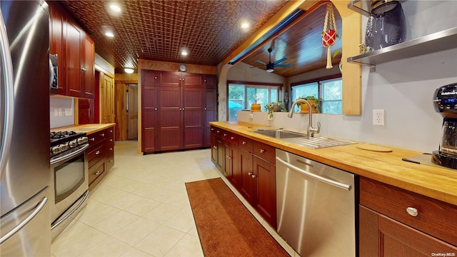 kitchen with ceiling fan, sink, butcher block countertops, lofted ceiling, and appliances with stainless steel finishes