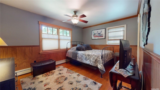 bedroom featuring baseboard heating, ceiling fan, light hardwood / wood-style floors, and ornamental molding