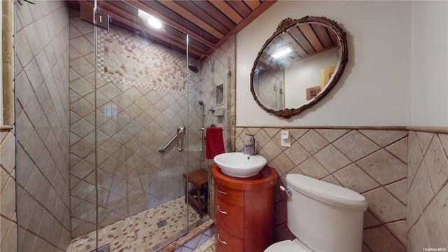 bathroom with vanity, toilet, an enclosed shower, and tile walls