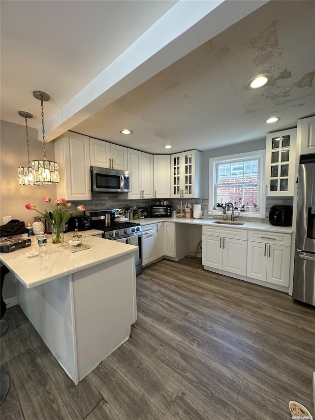 kitchen featuring sink, hanging light fixtures, stainless steel appliances, dark hardwood / wood-style flooring, and white cabinets