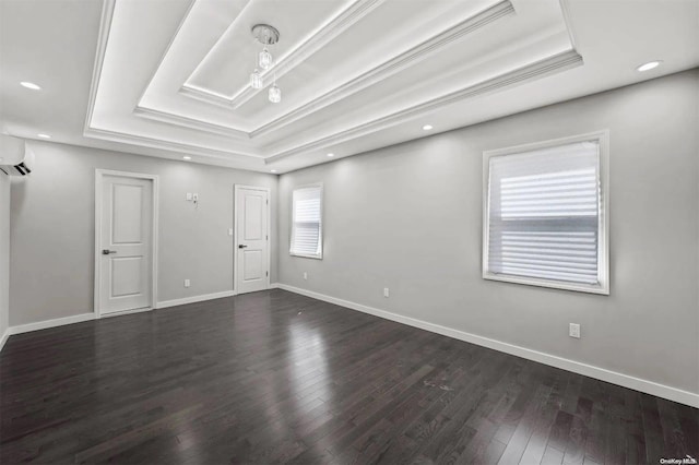 spare room with a raised ceiling, dark hardwood / wood-style flooring, a wall mounted air conditioner, and crown molding