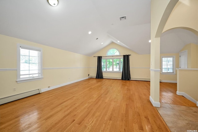 additional living space featuring lofted ceiling, a baseboard heating unit, and light hardwood / wood-style flooring