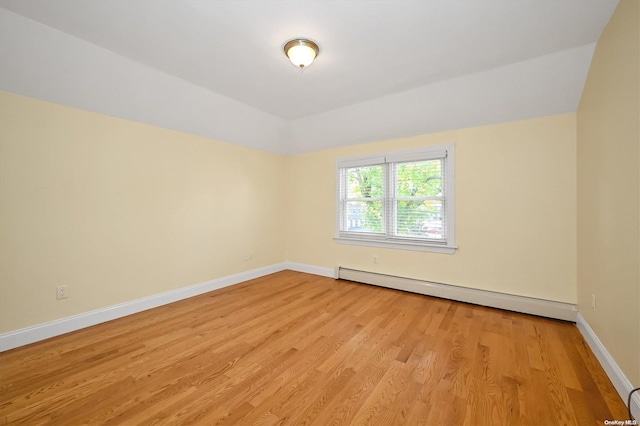 unfurnished room with a baseboard heating unit and light hardwood / wood-style floors