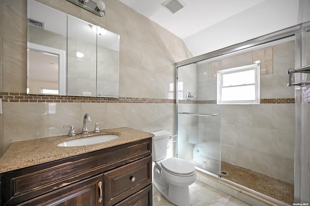 bathroom with tile walls, vanity, toilet, and walk in shower