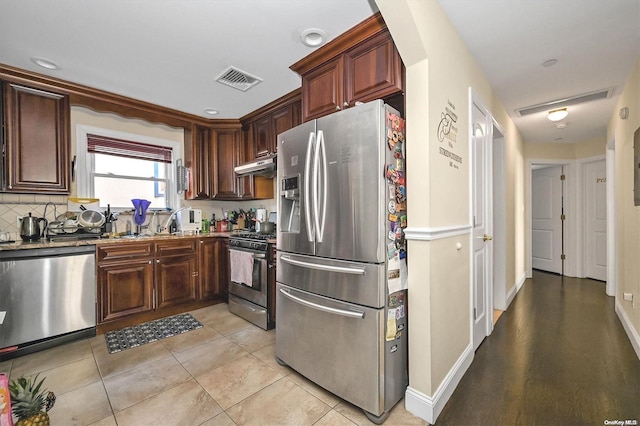 kitchen featuring light tile patterned floors, sink, appliances with stainless steel finishes, backsplash, and stone countertops