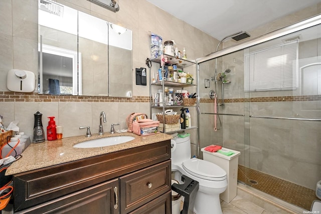 bathroom featuring tasteful backsplash, toilet, a shower with shower door, and tile walls