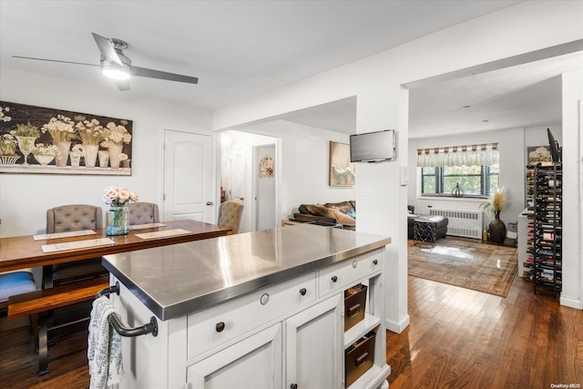 kitchen with white cabinets, dark hardwood / wood-style floors, ceiling fan, stainless steel counters, and radiator heating unit