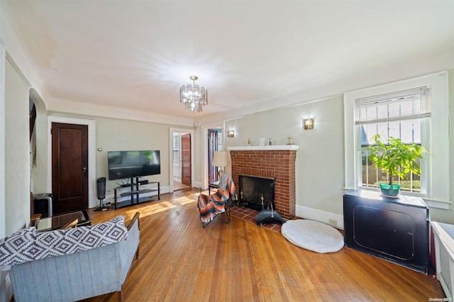 living room featuring hardwood / wood-style floors, a fireplace, and an inviting chandelier